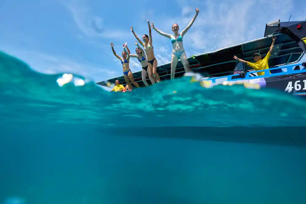 Guests cheering on the boat's platform with the reef below the surface