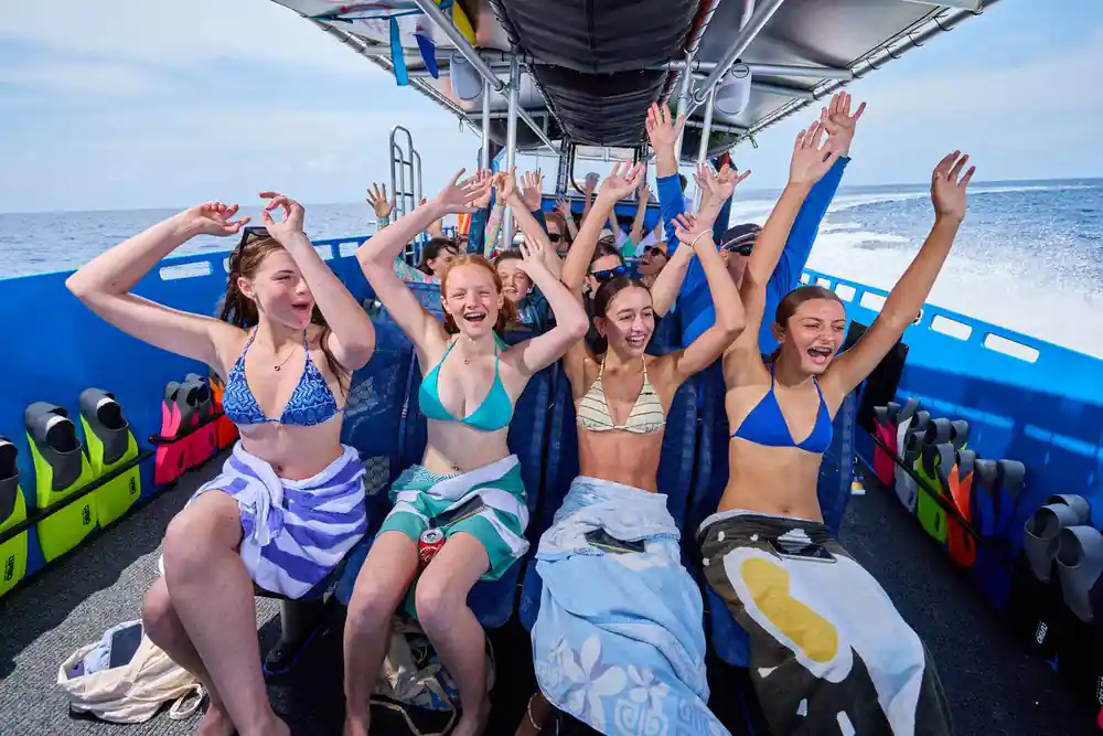 A row of guests cheering under the boat's canopy on the way out