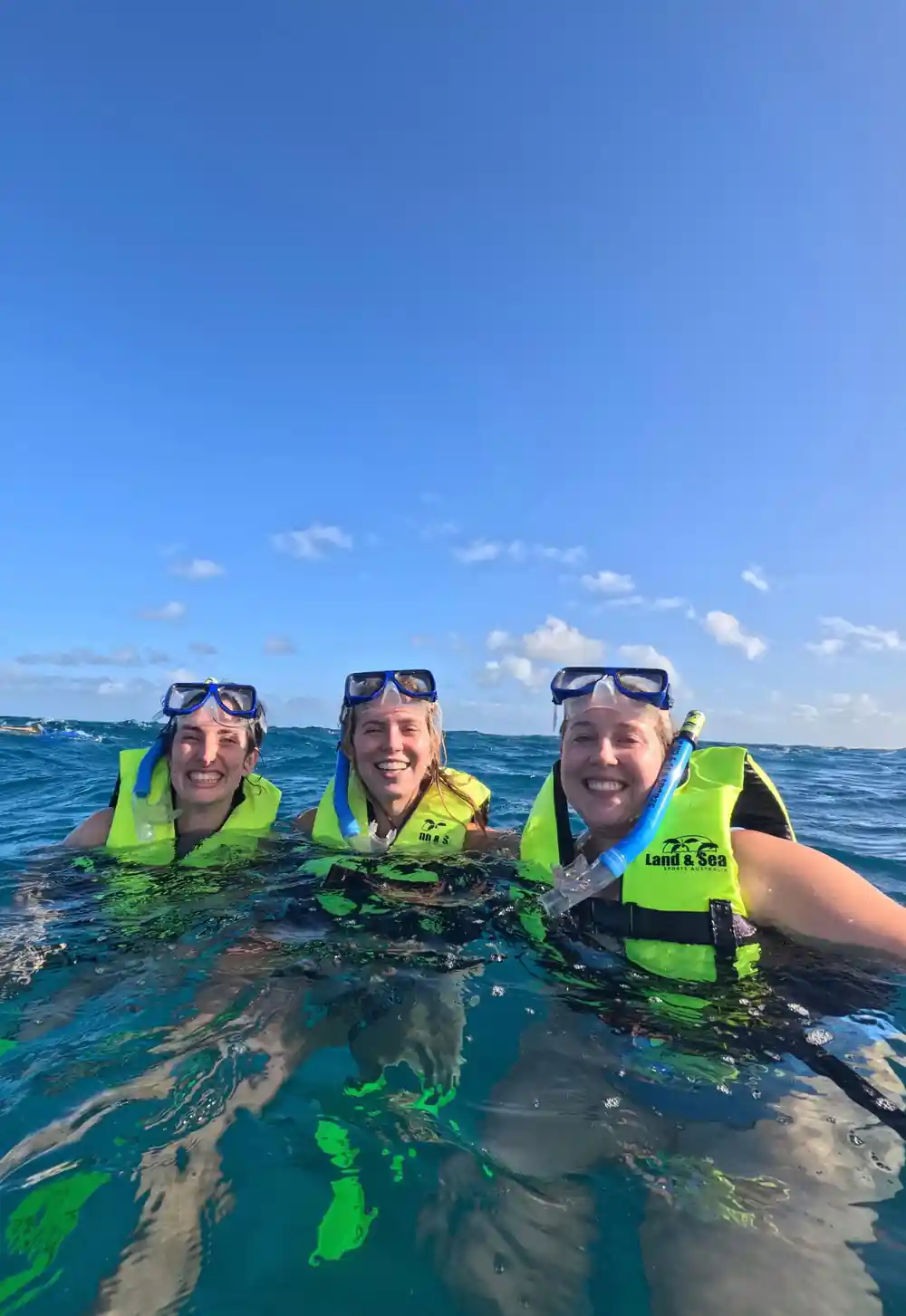 Three guests in flotation vests smiling at the surface