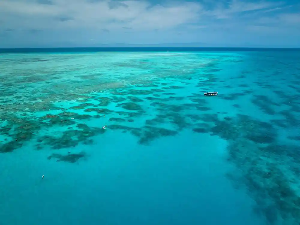 A wide reef flat with the boat small in the distance